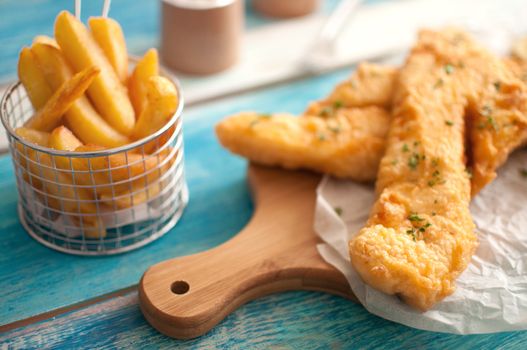 Two pieces of cod fried in batter with chips in a basket