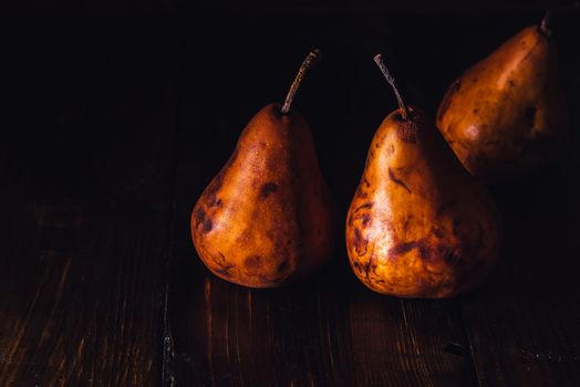 Three Golden Pears on Dark Wooden Table.