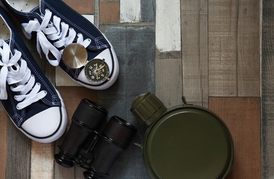 Pair of keds on color wooden background near compass and binoculars