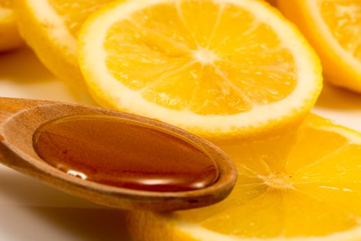 Closeup of sliced lemon and wooden spoon with honey