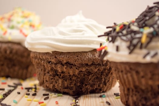 Muffin with cream and crumbs on top of it sitting on bright wooden table