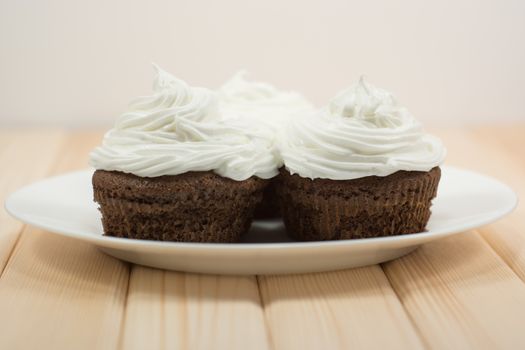 Muffins with cream on top of it sitting on bright wooden table