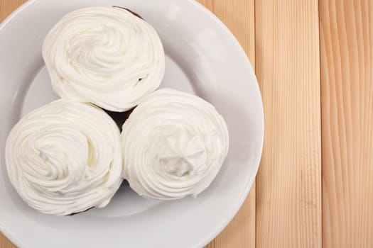 Muffins with cream on top of it sitting on bright wooden table