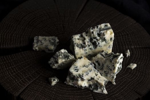 Pieces of danish blue cheese on black wooden background, with copy space