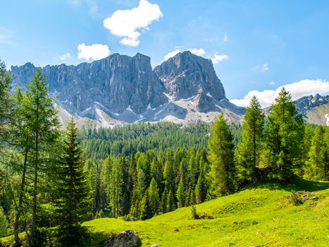 Lastoni de Formin, aka Ponta Lastoi de Formin. Giant mountain block with green meadow, trees and summer sky, Dolomites, Italy.