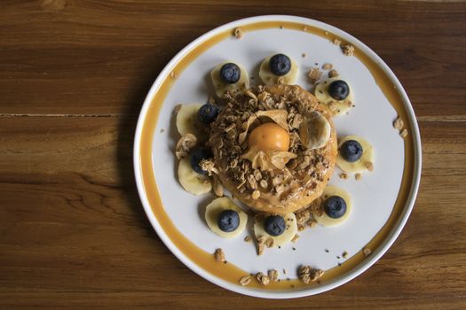 Overhead Shot Cake with Peanut Butter on top with Granola Banana and Berry on Wooden Table