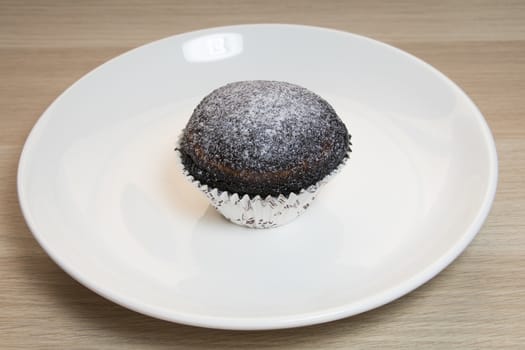 Close up on Chocolate Muffin cake with white plate on wooden Table