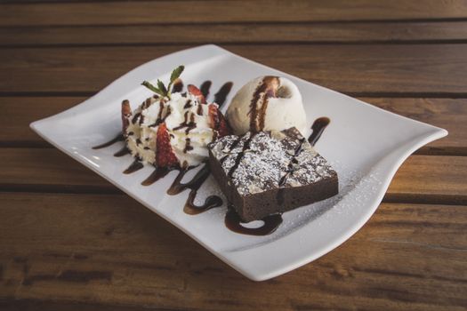 Chocolate brownies With whip cream and ice cream isolate on wood table