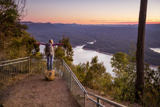 A hiker arrives at a lookout with views over river and mountain valley