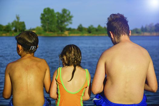 Children sitting on pier. Summer and childhood concept. Children at the lake. 