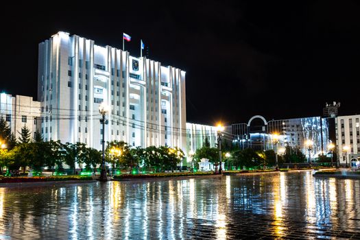 Night city landscape. The main square of the city of Khabarovsk in the light of lanterns, which are reflected in puddles after the rain just passed.