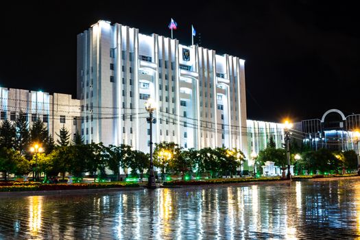 Night city landscape. The main square of the city of Khabarovsk in the light of lanterns, which are reflected in puddles after the rain just passed.