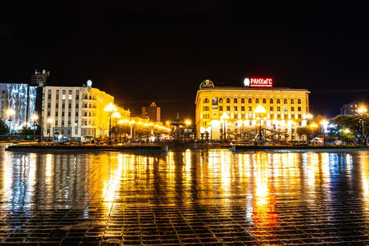 Night city landscape. The main square of the city of Khabarovsk in the light of lanterns, which are reflected in puddles after the rain just passed.