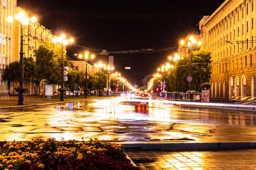 Night city landscape. The main square of the city of Khabarovsk in the light of lanterns, which are reflected in puddles after the rain just passed.