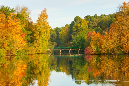 Scenic lake, autumn forest and bridge at sunset