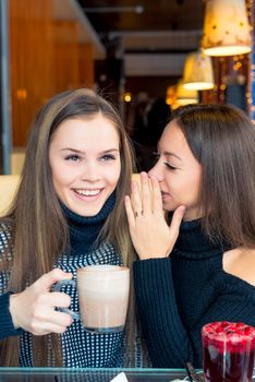 A girl tells her friend important secrets in a cafe