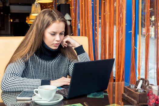 Businessman at a cafe working with laptop and drinking coffee