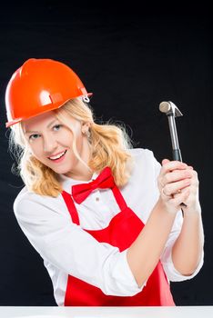 Vertical portrait of a charming chef in helmet with a hammer on a black background