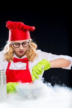 Woman animator cook doing experiments with liquid nitrogen, portrait on black background