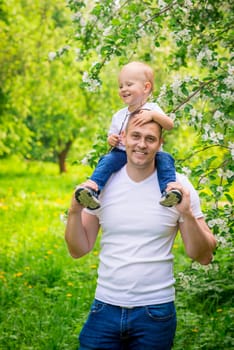 Vertical portrait of a happy father with a young son in a park on a walk