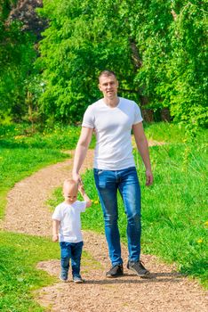 man with his son in a summer park on a sunny day on a walk