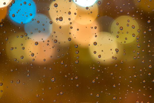 Glass with raindrops close-up macro, in the background lights