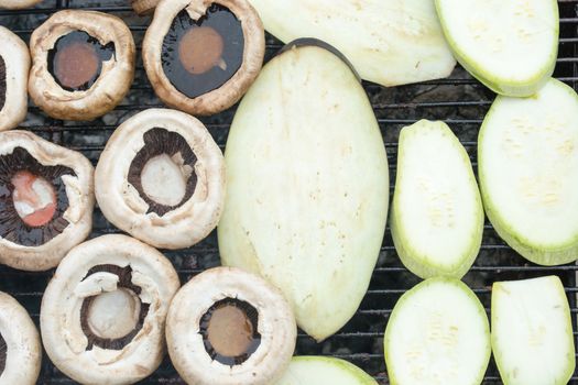 Grilling zucchini and mushrooms. Smoke visible. Upper angle