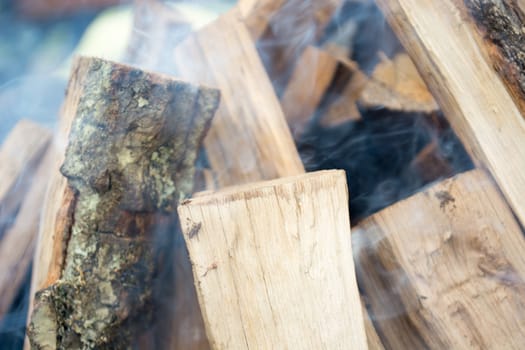Closeup of logs smoking and burrning in preparation for nice barbecue