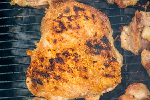 Closeup of grilled pork chop. Meat is still smoking on grill