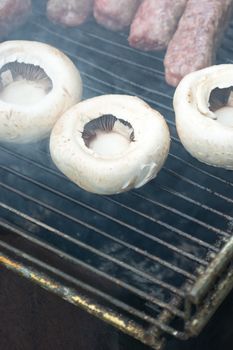 Grilling cevapi and mushrooms. Closeup. Smoke visible