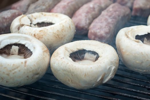 Grilling cevapi and mushrooms. Closeup. Smoke visible