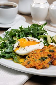 Brunch Idea. Egg poached with pumpkin spinach pancakes and garnish from arugula, avocado, mint leaves, and ricotta