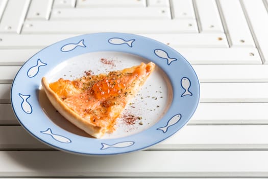 Pizza sliced with smoked salmon and egg on white wooden table