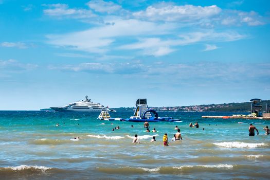 Luxury sand beach in Borik, Zadar Croatia, people sunbathing and swimming, luxury hotels in background righ next to the beach. District of Puntamika