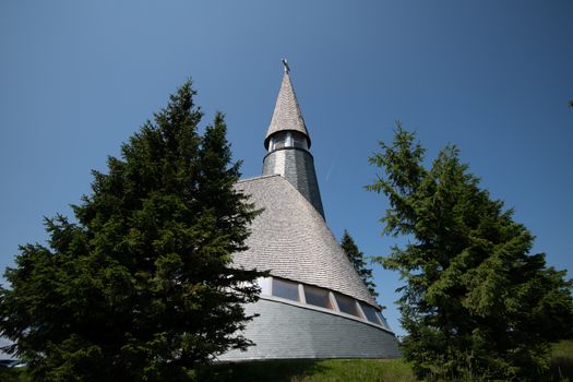 Church of Jesus Christ at Rogla ski resort.Pohorje, Slovenia, Europe, summer, against blue sky and framed between two trees
