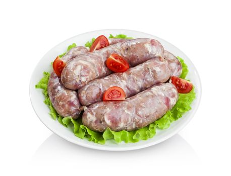Sausages raw for grilling on plate with lettuce and cherry tomatoes isolated on white background