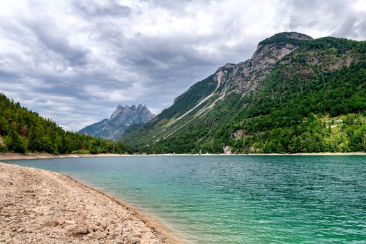 Alpine glacier lake with turquoise water and mountains in background on cloudy, overcast day, European Alps, Lake Predil near Tarvisio in Italy