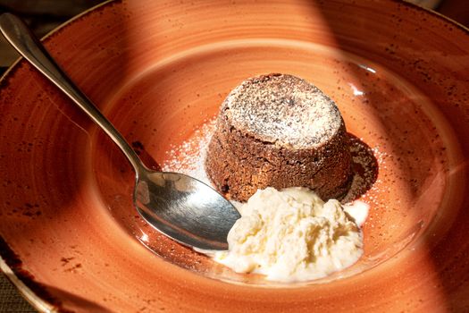 chocolate souffle on brown plate with whipped cream, close up shot, framed with light and shadow
