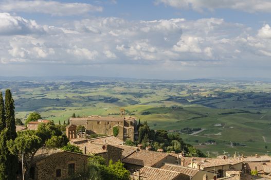 Rooftops of Montalcino and scenic view of typical Tuscany landscape in Val D'Orcia: hills, meadows and green fields. Tuscany, Italy, Europe