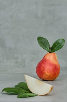 Ripe red pears with green leaves on the gray background