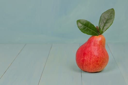 Ripe red pears with green leaves on wooden table