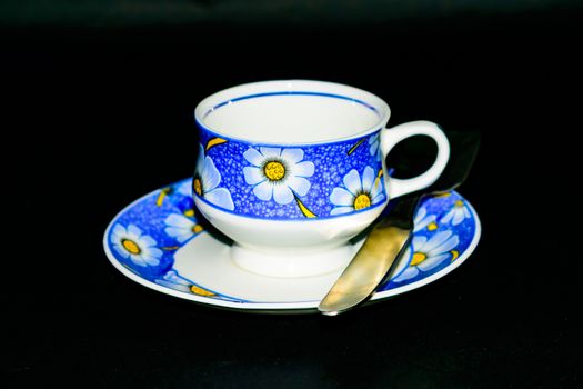 Single coffee cup on the plate with spoon in dark background