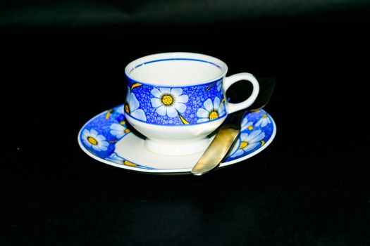 Single coffee cup on the plate with spoon in dark background