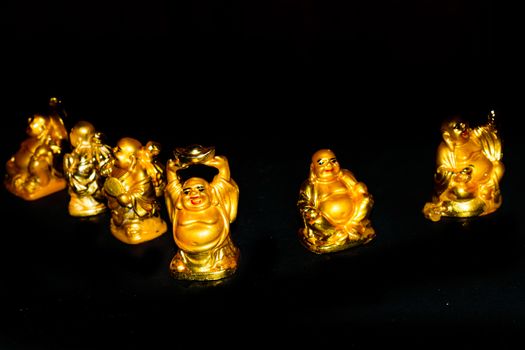 A Golden Laughing Buddhas with relaxed mindset. Isolated in a dark background. Selective focus and shallow depth of field