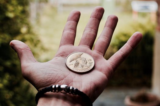 Digital currency physical gold bitcoin coin in man hand with black bracelet.