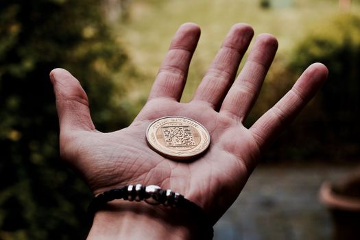 Digital currency physical gold bitcoin coin in man hand with black bracelet.