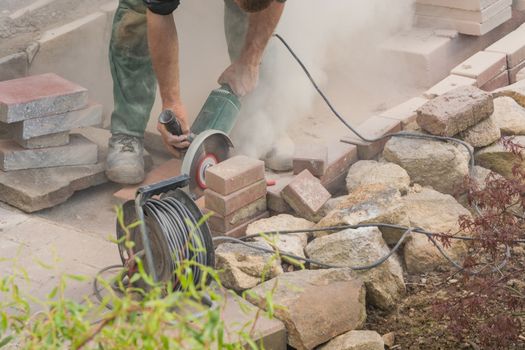 Man cutting stone slabs, concrete slab with an electric grinder