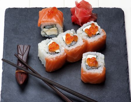 Delicious Sushi with Smoked Sliced Salmon and Gourmet Red Caviar on Serving Stone Plate with Chopsticks and Ginger closeup
