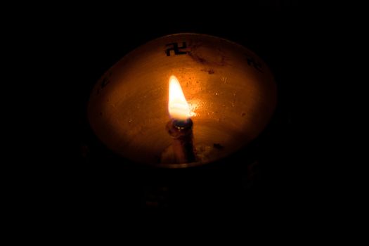 Flame of oil lamp on dark background, a burning oil lamp in darkness, with copy space. concept of removing darkness with a flame, are common in india and nepal for festival usage.