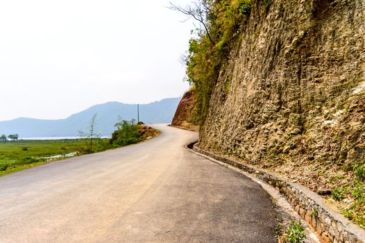 Photograph of empty road with hill in surrounding near Pokhara Lake at Kathmandu Nepal. Snap in portrait, landscape, wide screen style. Vintage film look. Vacation Freedom, Simplicity Concept.